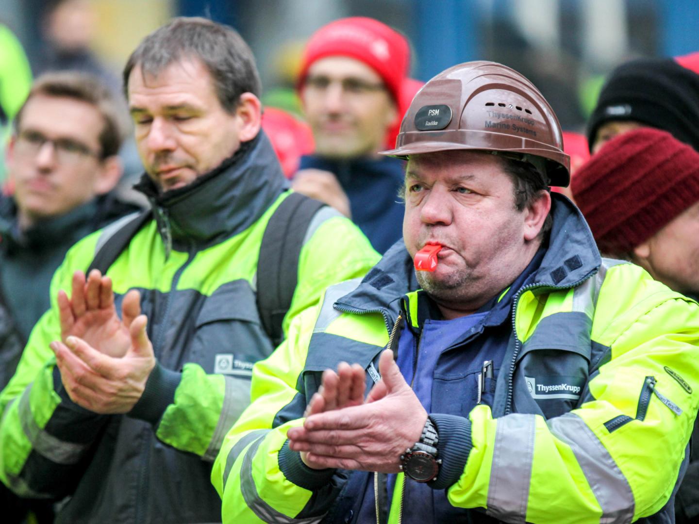 Ein Mann in Schutzkleidung mit Helm und einer Pfeife im Mund.