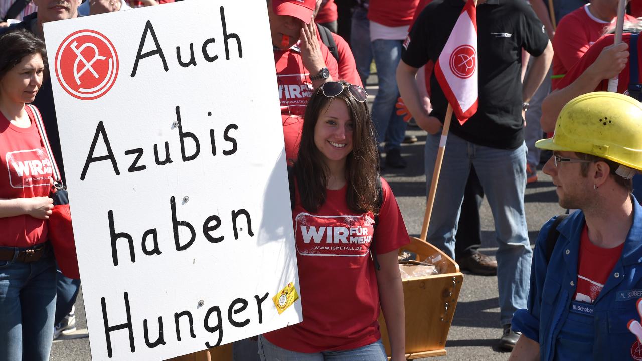 Junge Frau bei einem Warnstreik während der Tarifrunde mit einem Transparent mit der Aufschrift 
