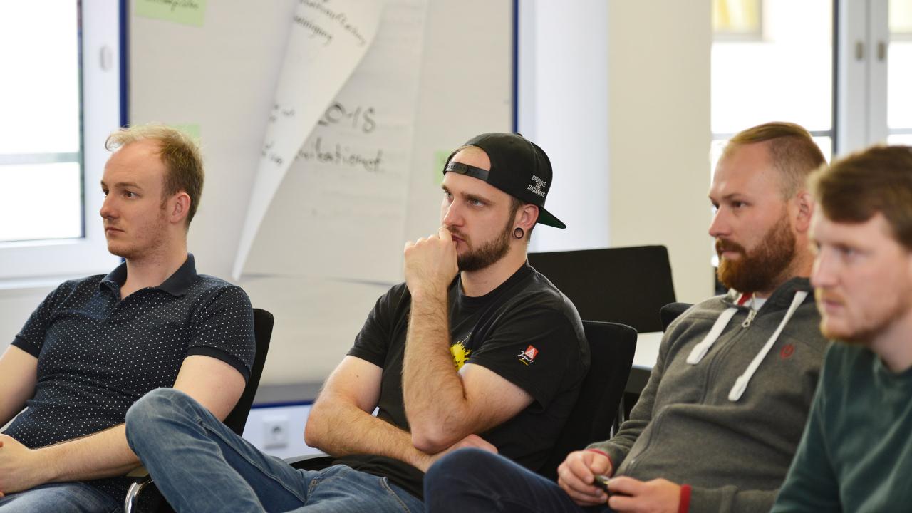 Junge Aktive sitzen während eines Seminars im Stuhlkreis und hören zu.