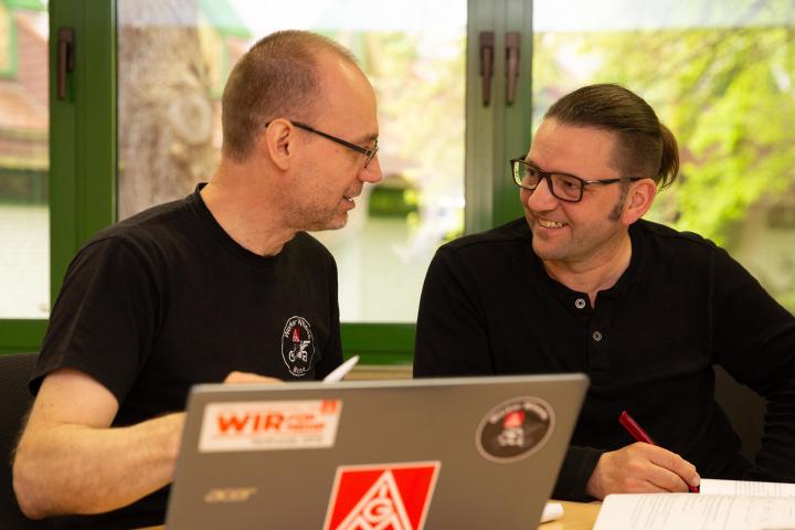 Zwei Beschäftigte sitzen an einem Tisch vor einem Laptop