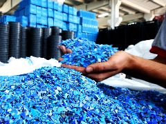 Eine Hand hält blaues Kunststoffgranulat.