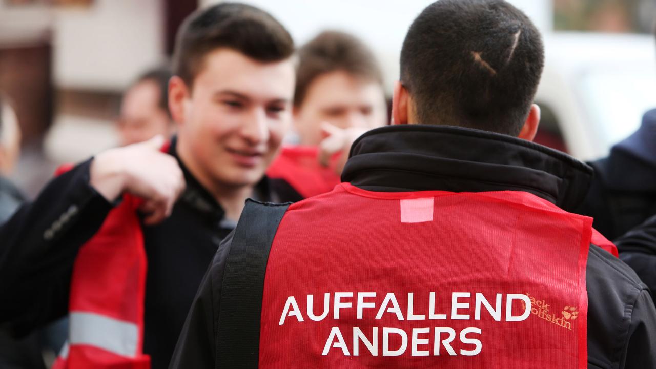 Junger Mann mit roter Weste mit der Aufschrift 