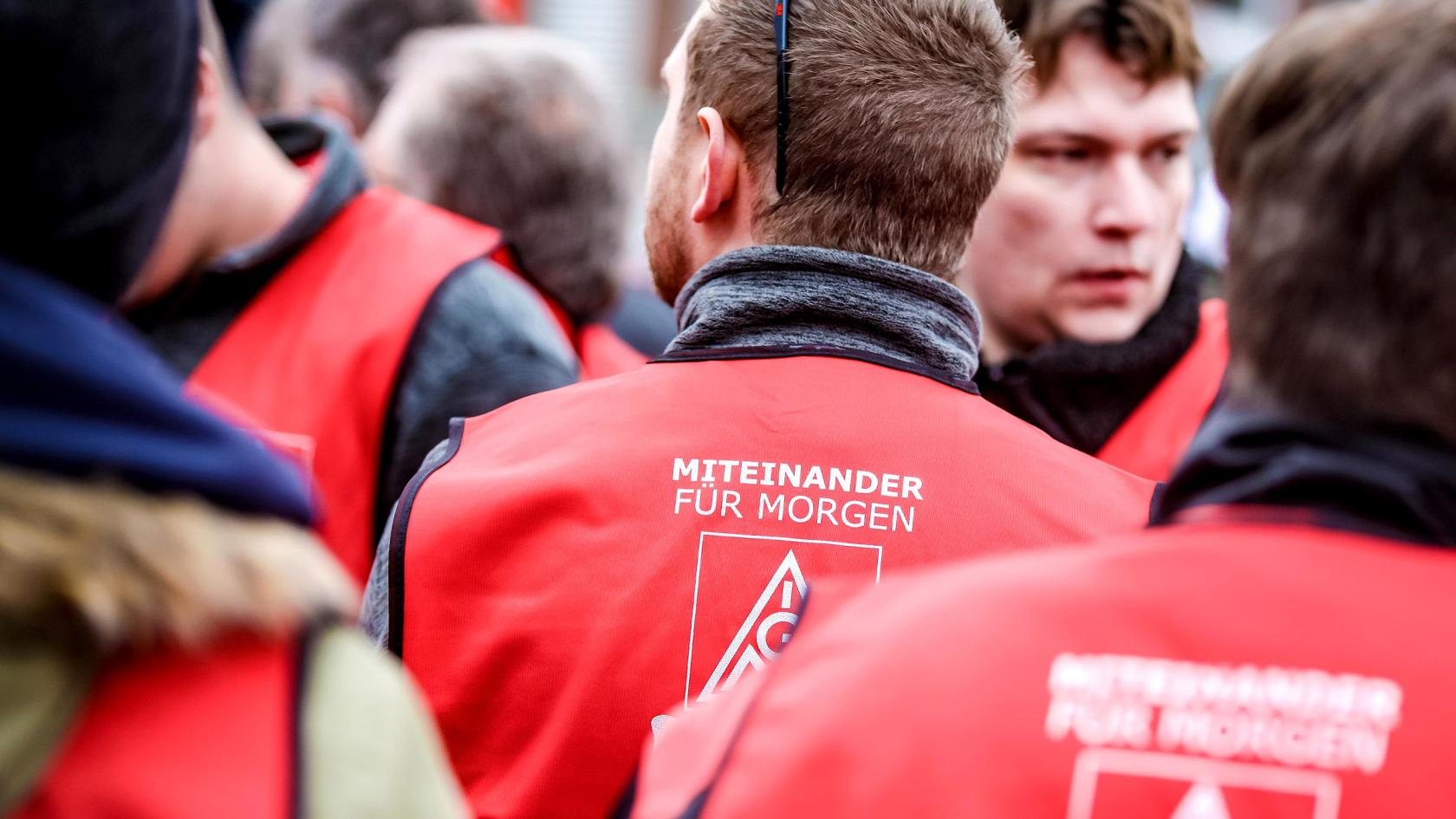 Mehrere Männer mit roten Westen auf denen 