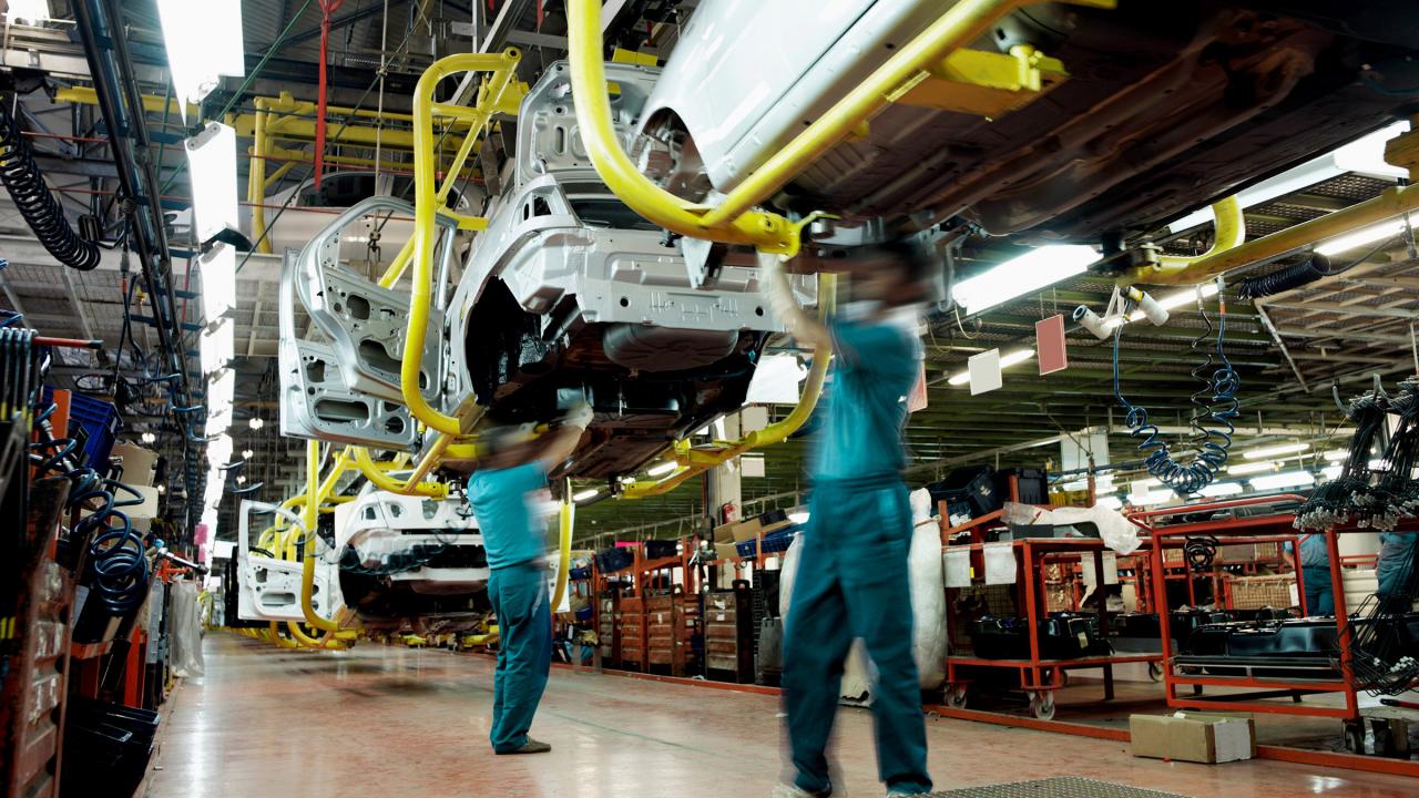 Zwei Männer arbeiten an Karosserien in einer Autofabrik.
