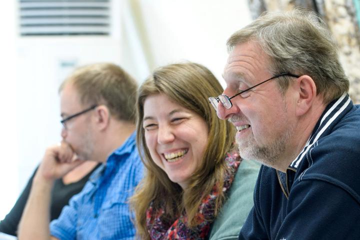 Drei ältere Männer und eine Frau lachend während eines Seminars.