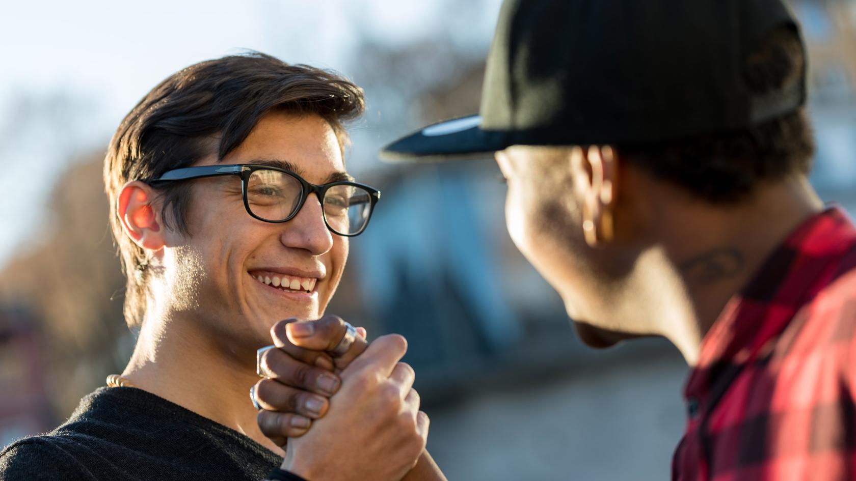 Zwei junge Männer geben sich freudig die Hand