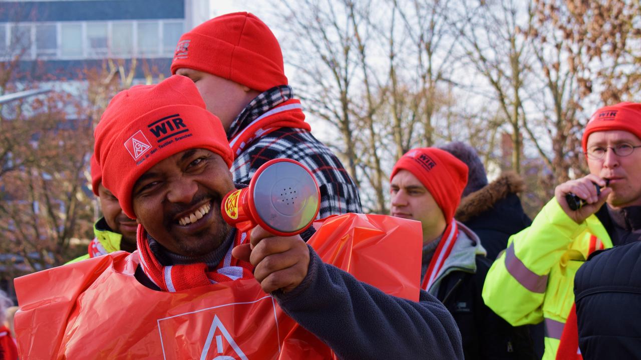 Mann hält ein Megafon auf dem Warnstreik der Textilindustrie in Fulda