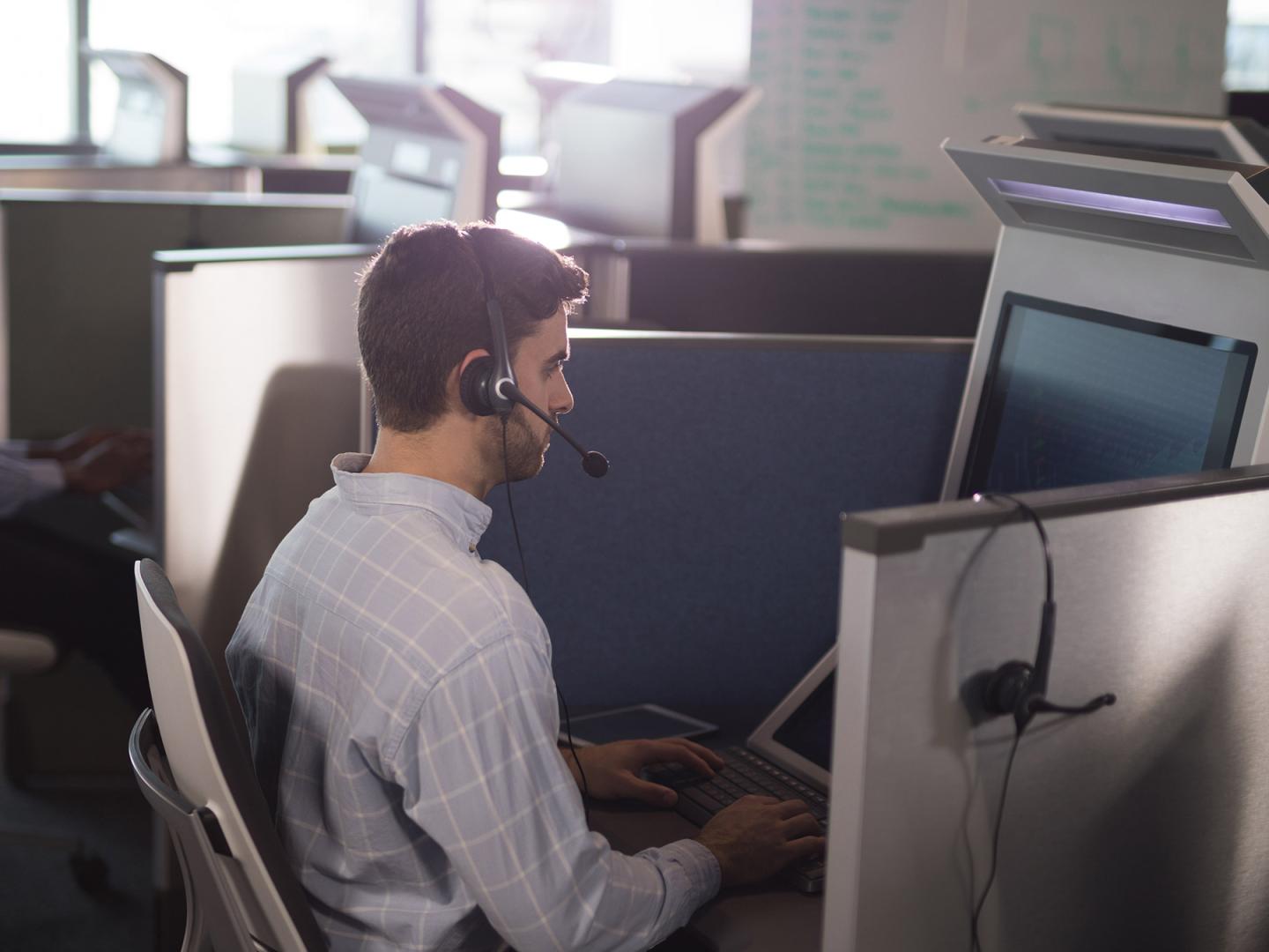 Mann sitzt mit seinem Headset vor einem PC