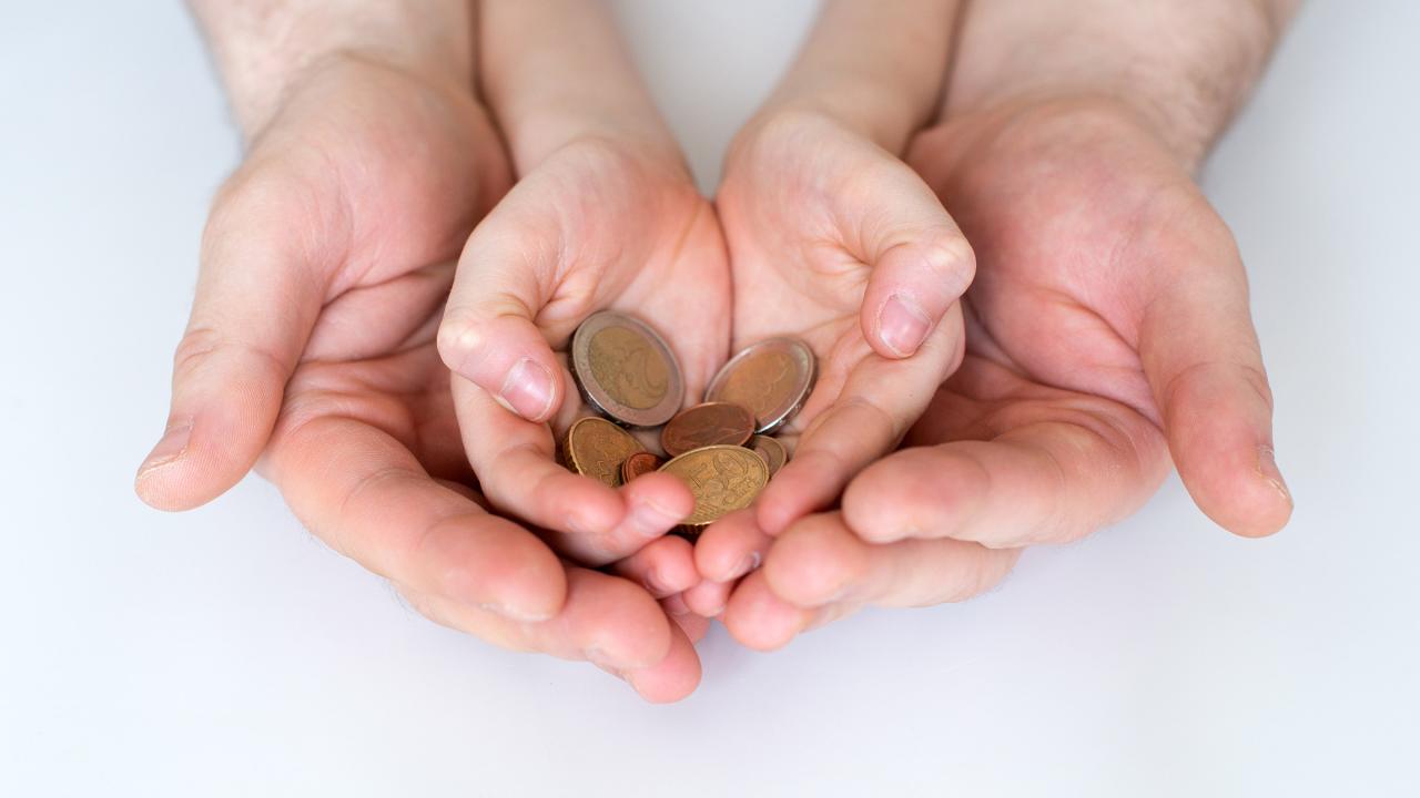 Vater und seiner Kind halten Euro-Münzen in den Händen