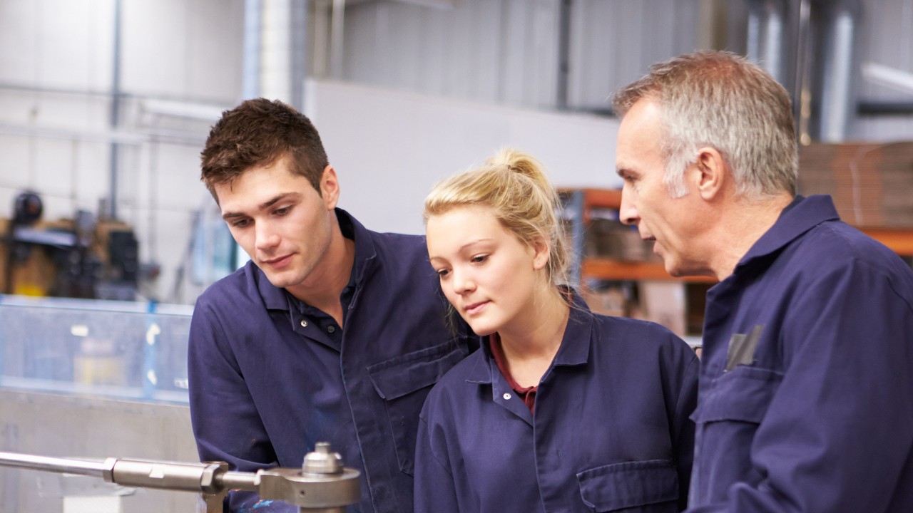 Ingenieur erklärt zwei Auszubildenden eine Maschine