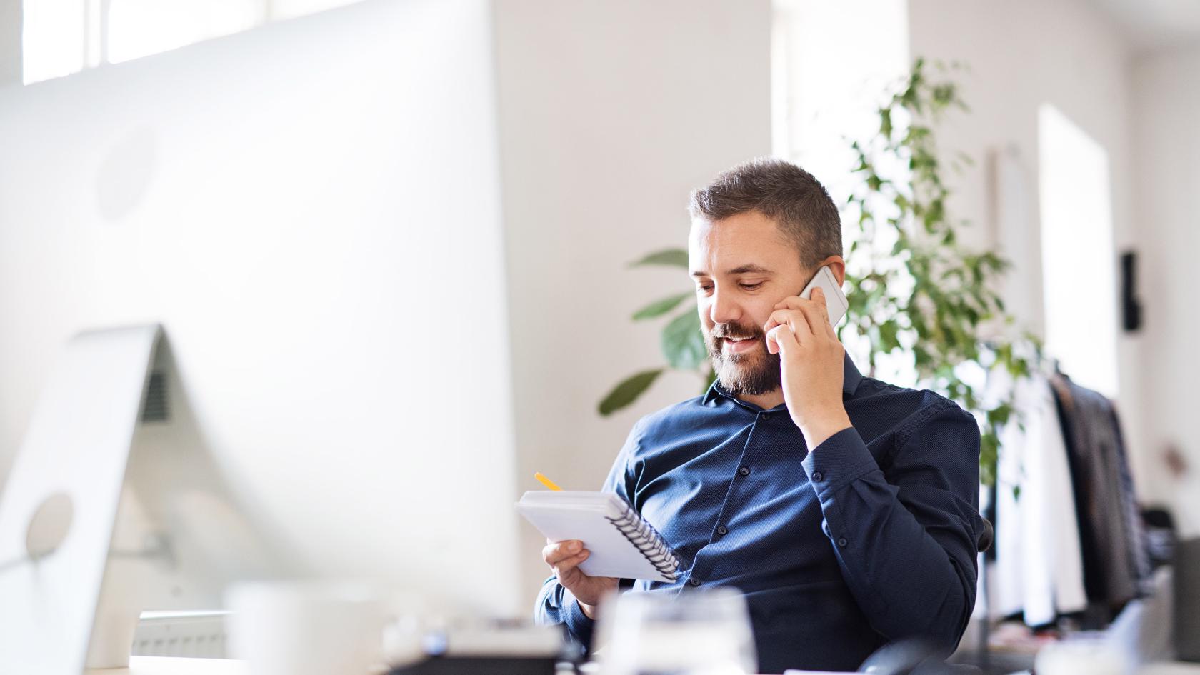 Mann telefoniert mit seinem Smartphone am Arbeitsplatz