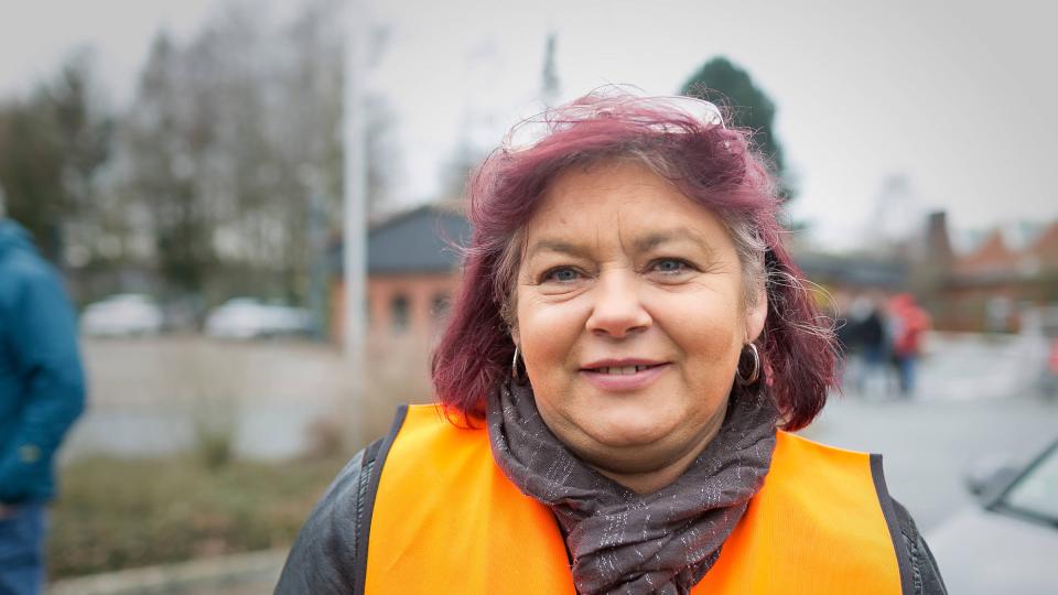 Brigitte Adena mit einer orangen Warnweste l&auml;chelt in die Kamera.