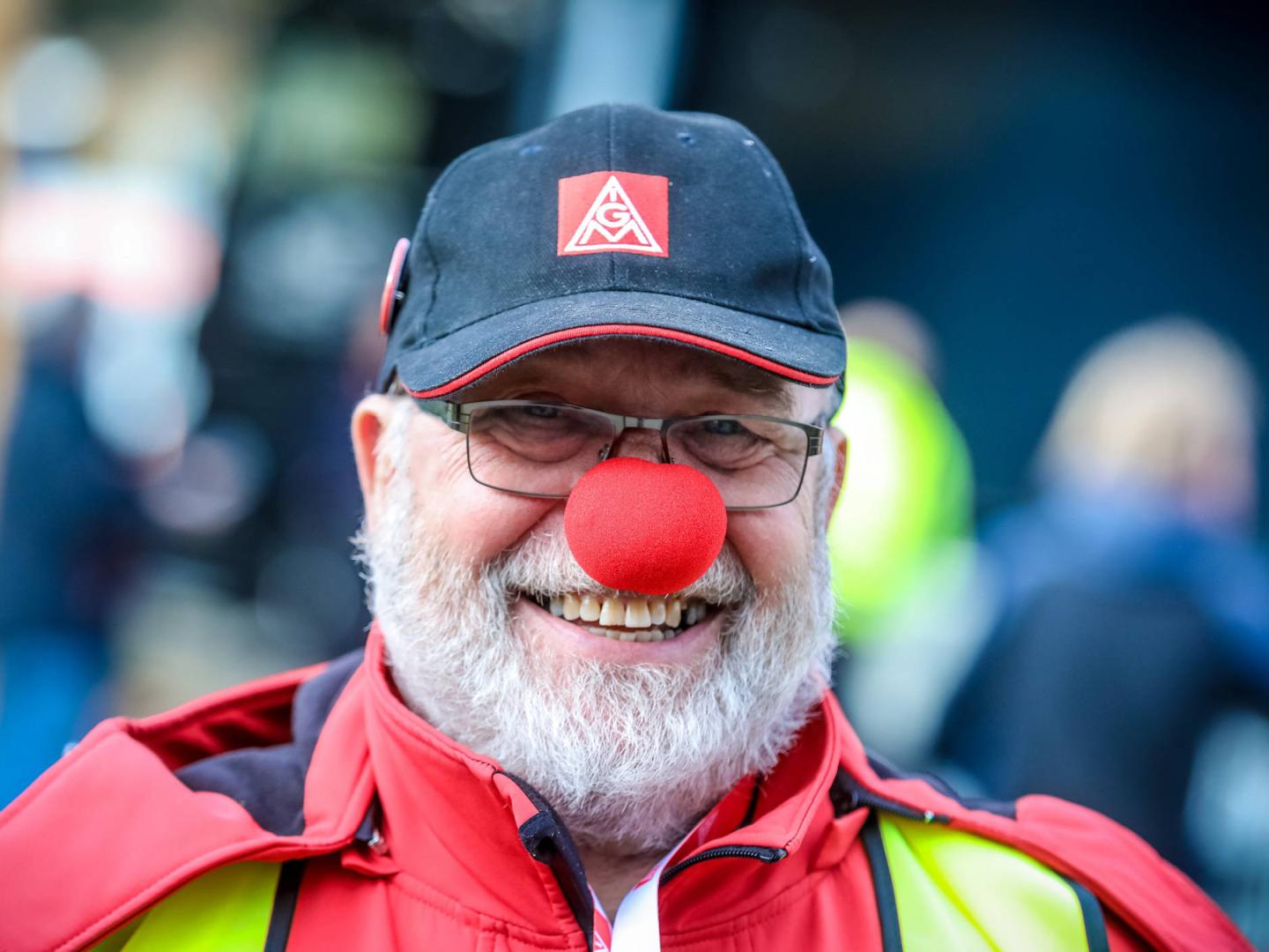 Ein lächelnder Mann mit roter Clownsnase und IG Metall-Kappe.