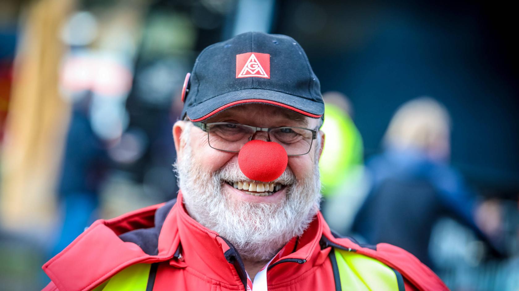 Ein lächelnder Mann mit roter Clownsnase und IG Metall-Kappe.