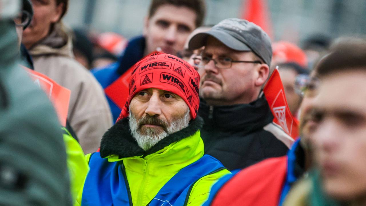 Ein Mann mit IG Metall-Kopftuch steht in einer Menschenmenge.