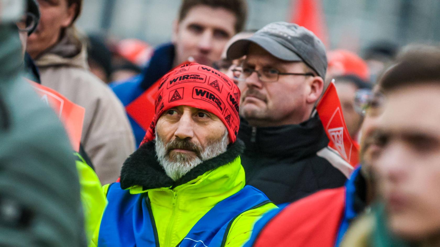 Ein Mann mit IG Metall-Kopftuch steht in einer Menschenmenge.