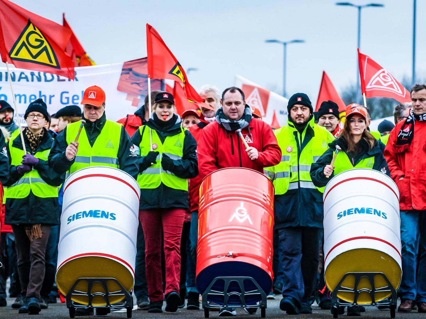 Streikende an der Spitze eines Demonstrationszuges, die auf Fässern trommeln.