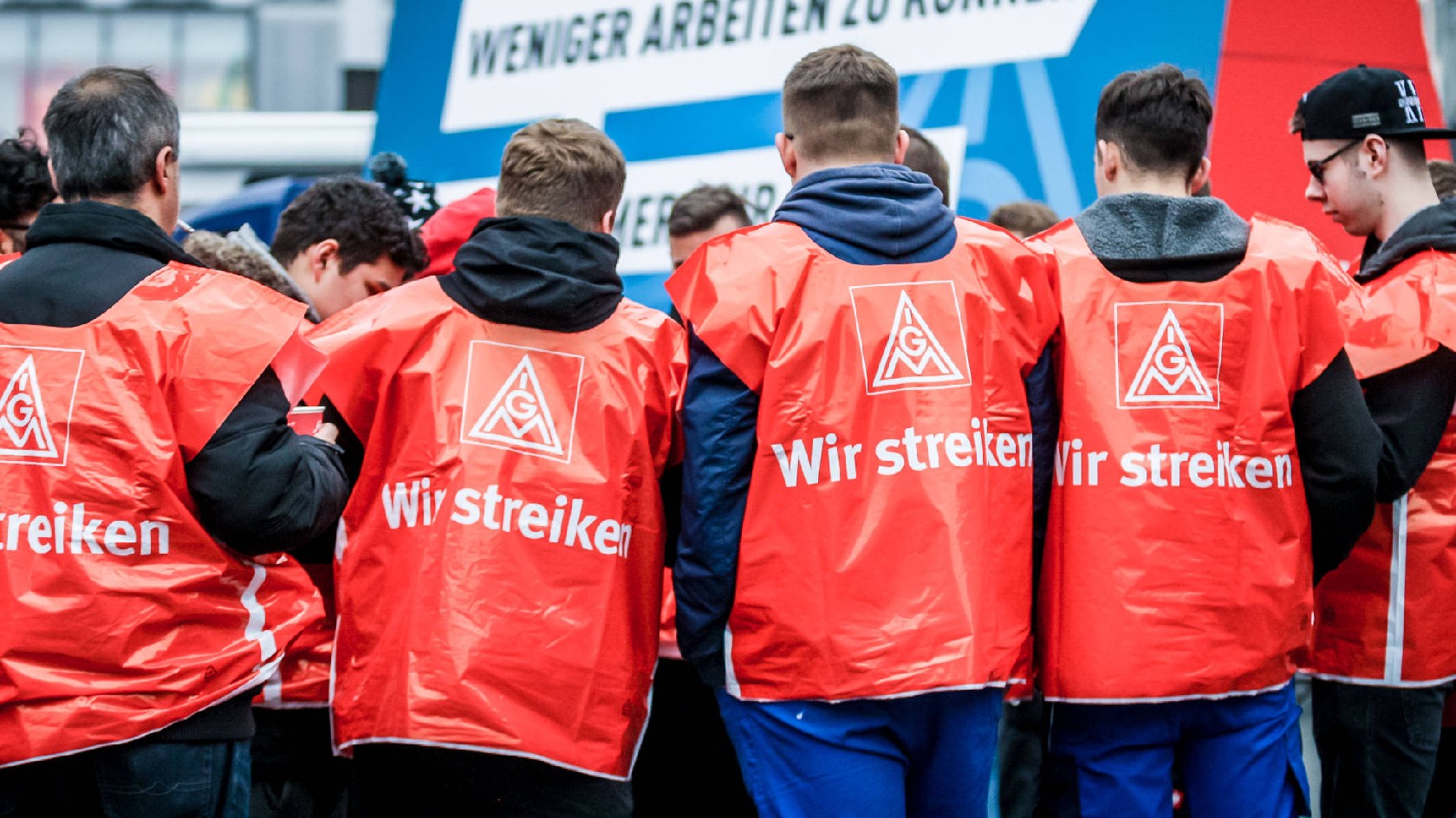 Eine Gruppe junge Männer mit roten Streikwesten.