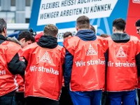Eine Gruppe junge Männer mit roten Streikwesten.