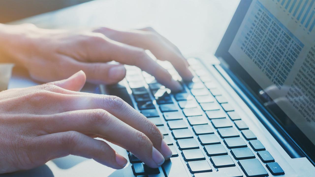 Mensch schreibt an einem Laptop