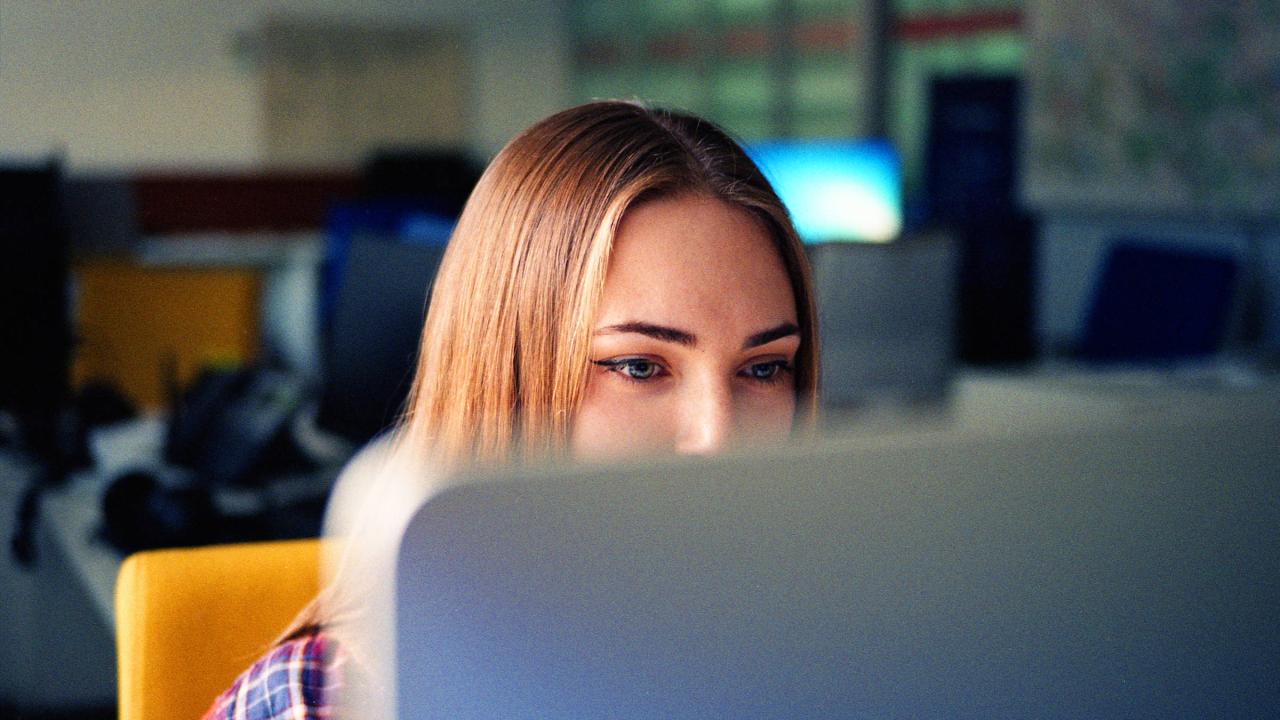 Eine junge Frau schaut in einen Bildschirm.