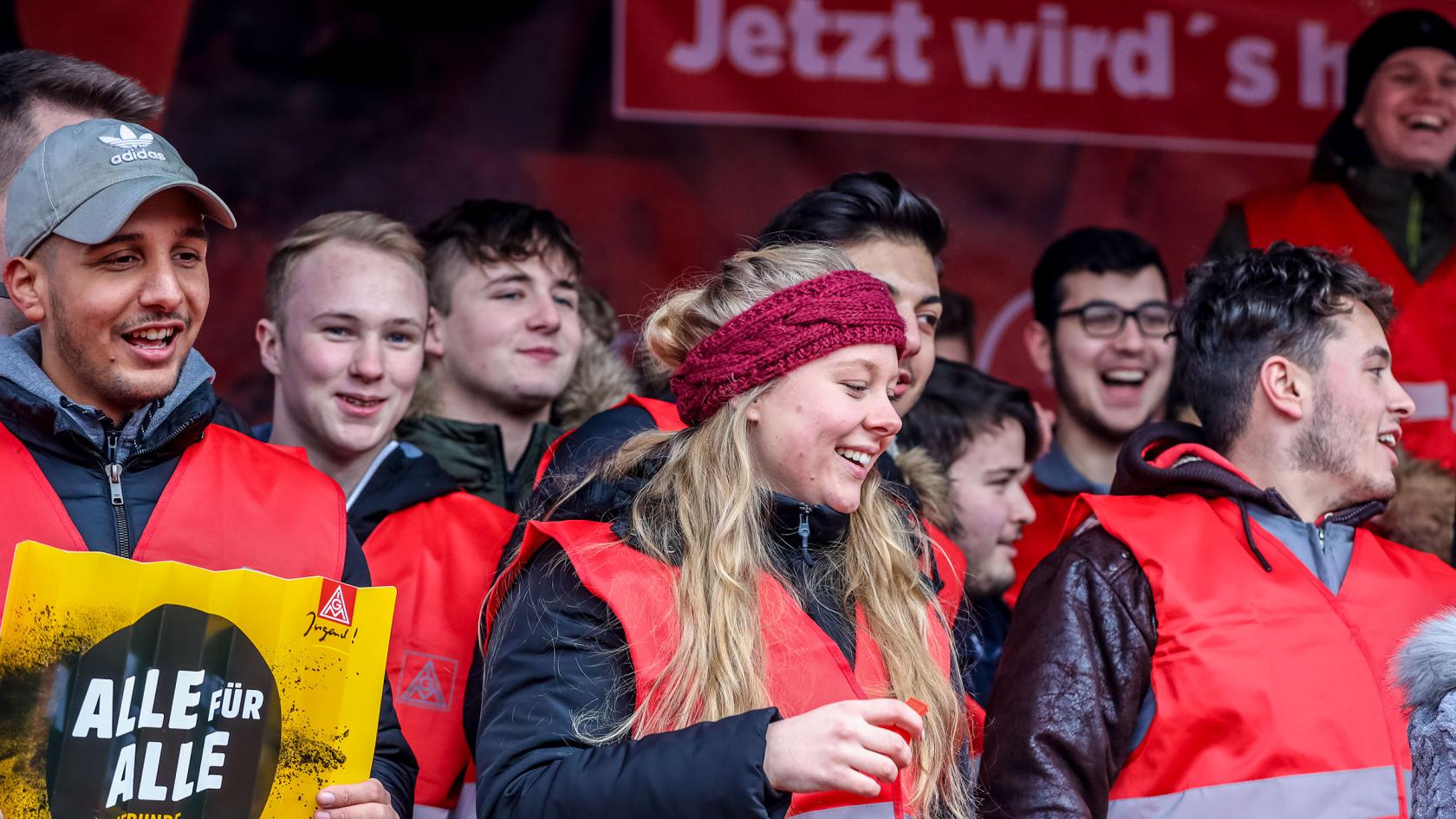 Eine Gruppe Jugendliche mit roten IG Metall-Westen. 