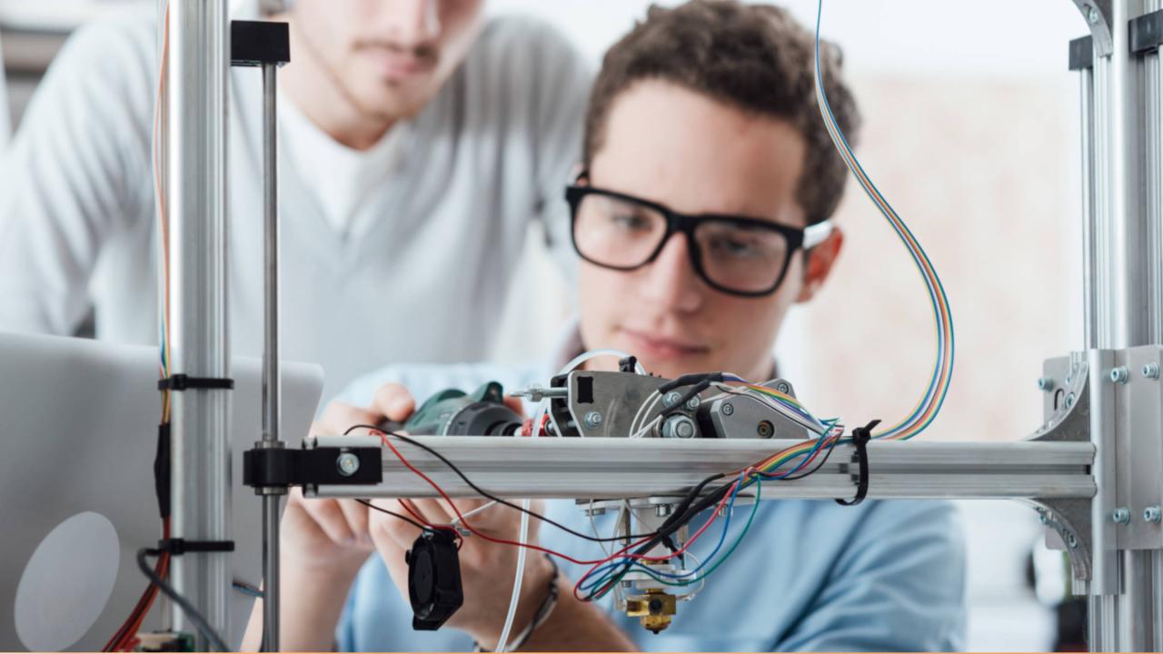 Ein junger Mann arbeitet an einem 3D-Drucker. 