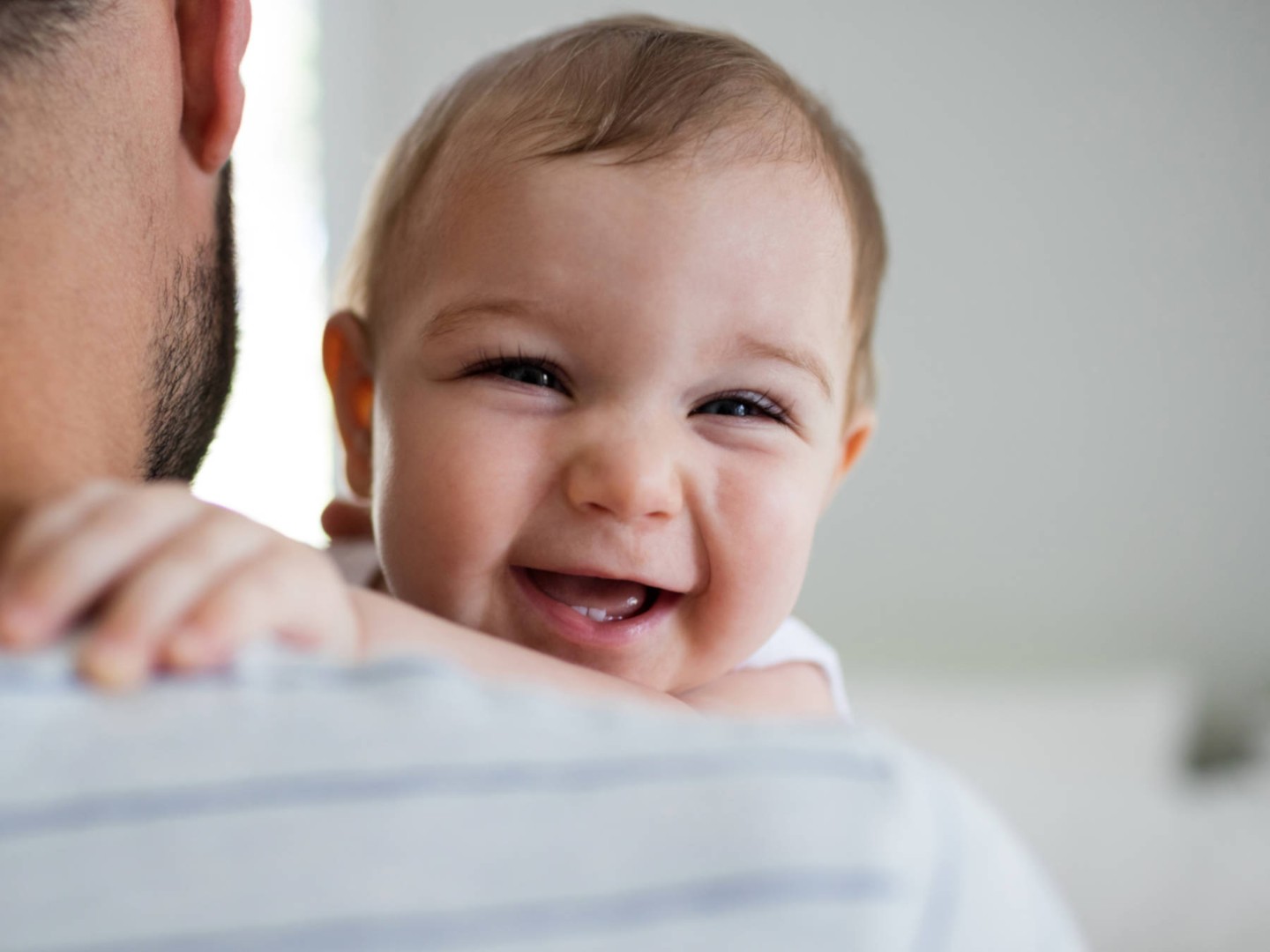 Ein lächelndes Baby auf dem Arm seines Vaters.