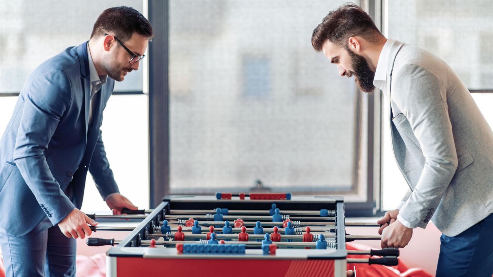 Zwei Kollegen spielen im Büro an einem Tischkicker