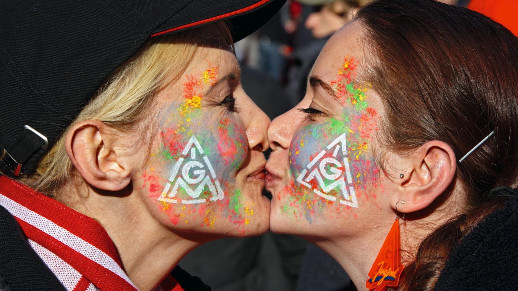 Zwei Frauen mit IG Metall-Logos auf der Backe küssen sich
