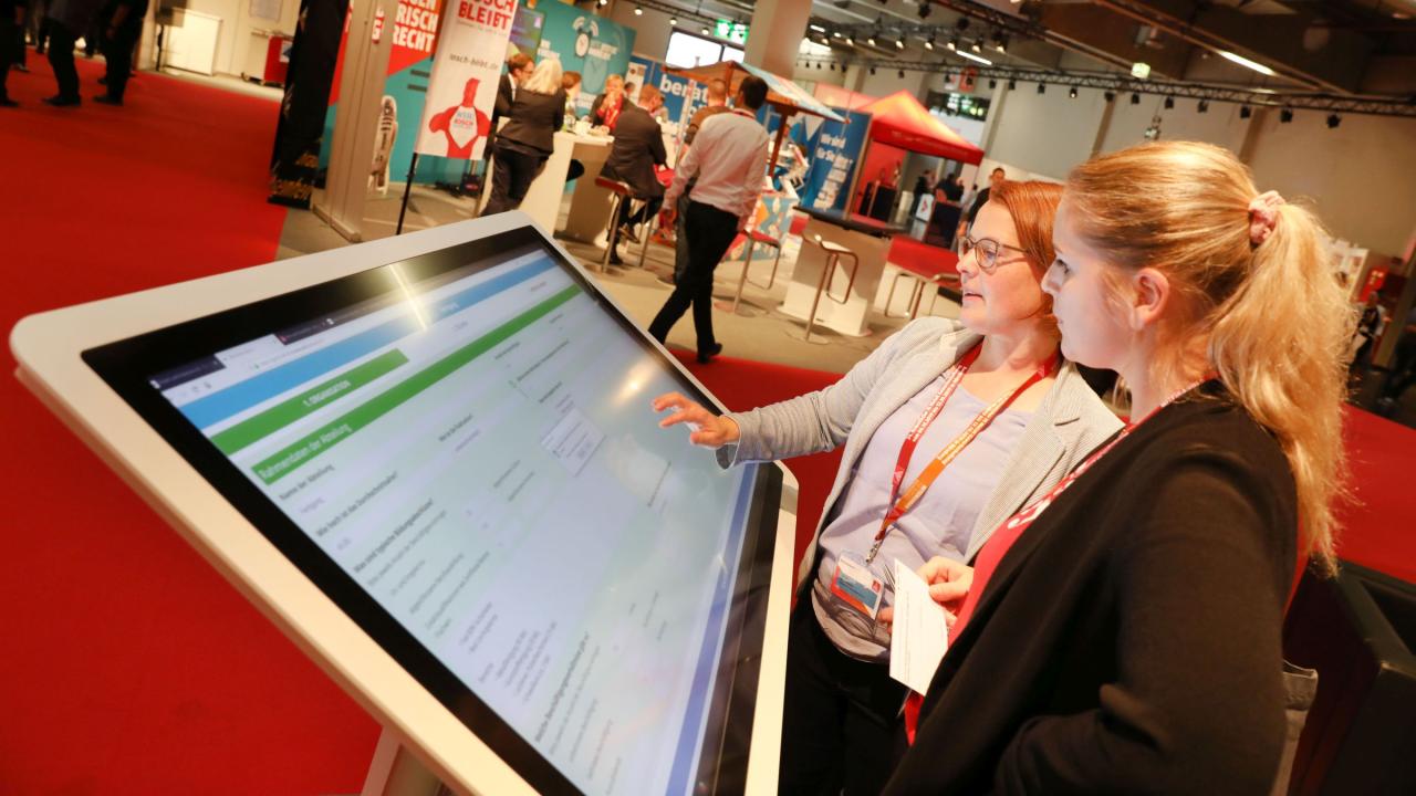 Zwei Delegierte bei der Bedienung eines Touch-Bildschirms auf dem Gewerkschaftstag 2019 der IG Metall