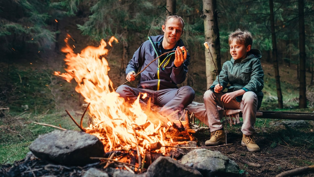 Vater und Sohn gemeinsam beim Marshmellowgrillen am Lagerfeuer