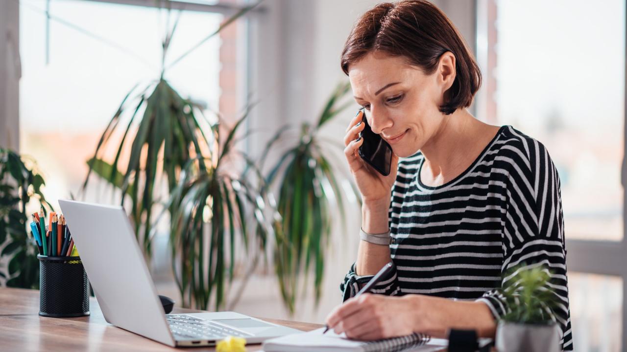 Frau sitzt im Homeoffice am Laptop und telefoniert