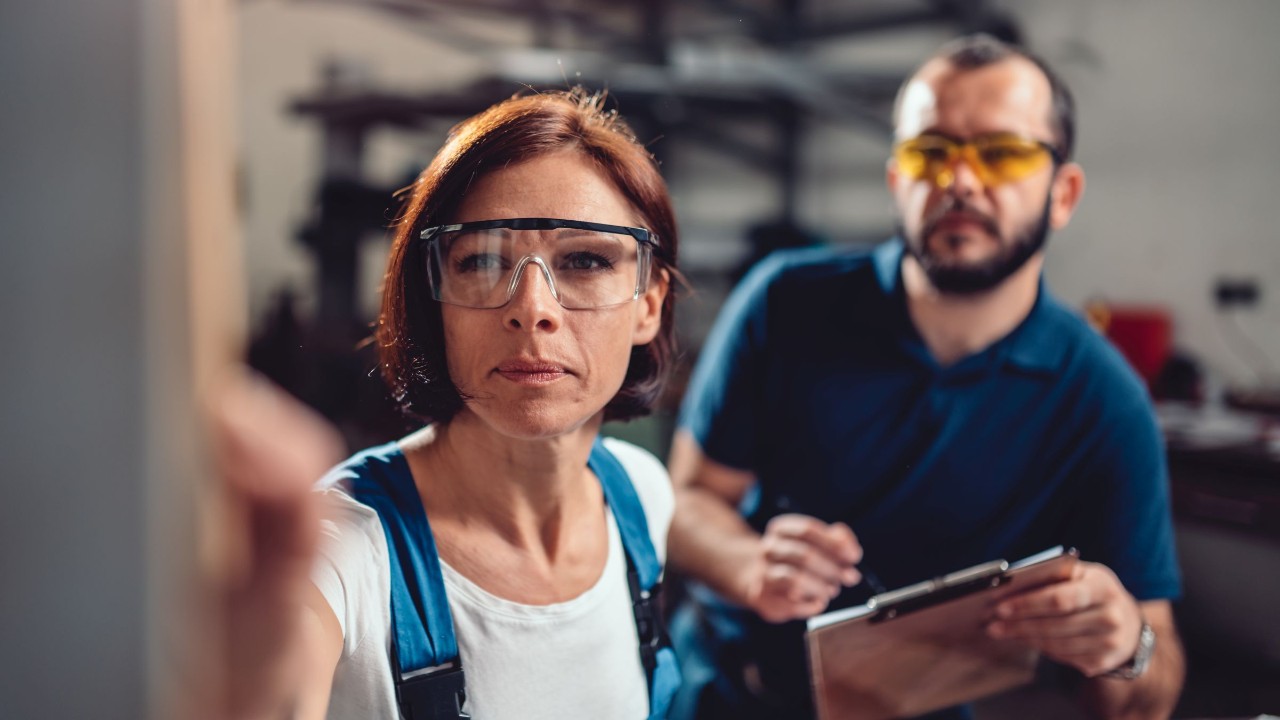 Arbeitnehmerin und Arbeitnehmer prüfen gemeinsam eine Maschine oder Bestand