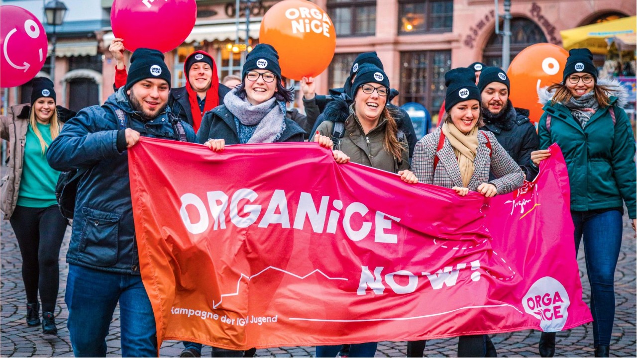 Junge Kollegixe / Menschen mit Transparent und Luftballon
