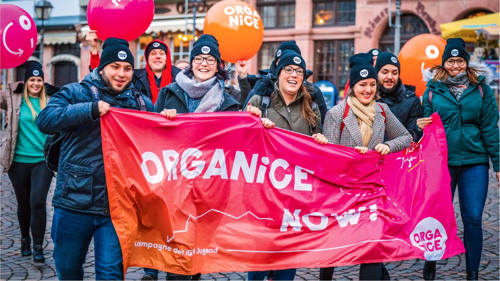 Junge Kollegixe / Menschen mit Transparent und Luftballon