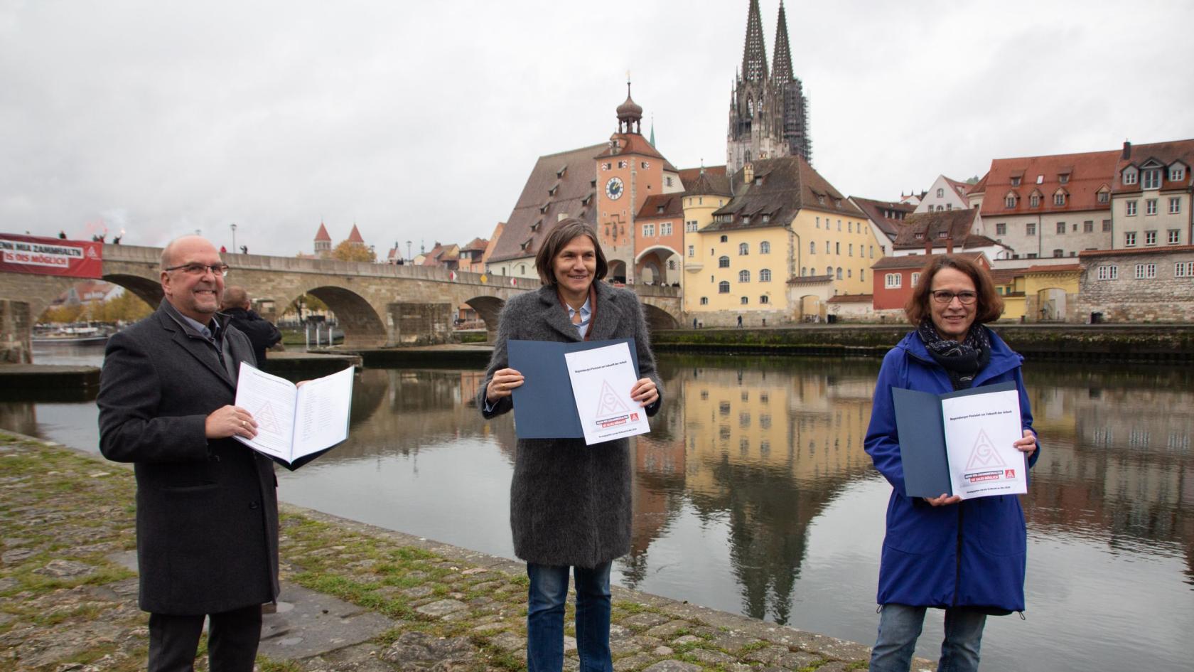 Mitten in Regensburgs Innenstadt an der Steinernen Brücke haben Christiane Benner, Zweite Vorsitzende der IG Metall, und Jürgen Scholz als Erster Bevollmächtigte der IG Metall Regensburg ein Postulat zur Zukunft der Arbeit an die Oberbürgermeisterin der Stadt übergeben.