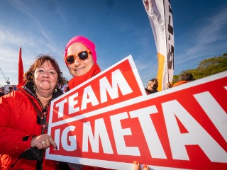 Zwei Metallerinnen mit Schild Team IG Metall in Hamburg beim Aktionstag Fairwandel.