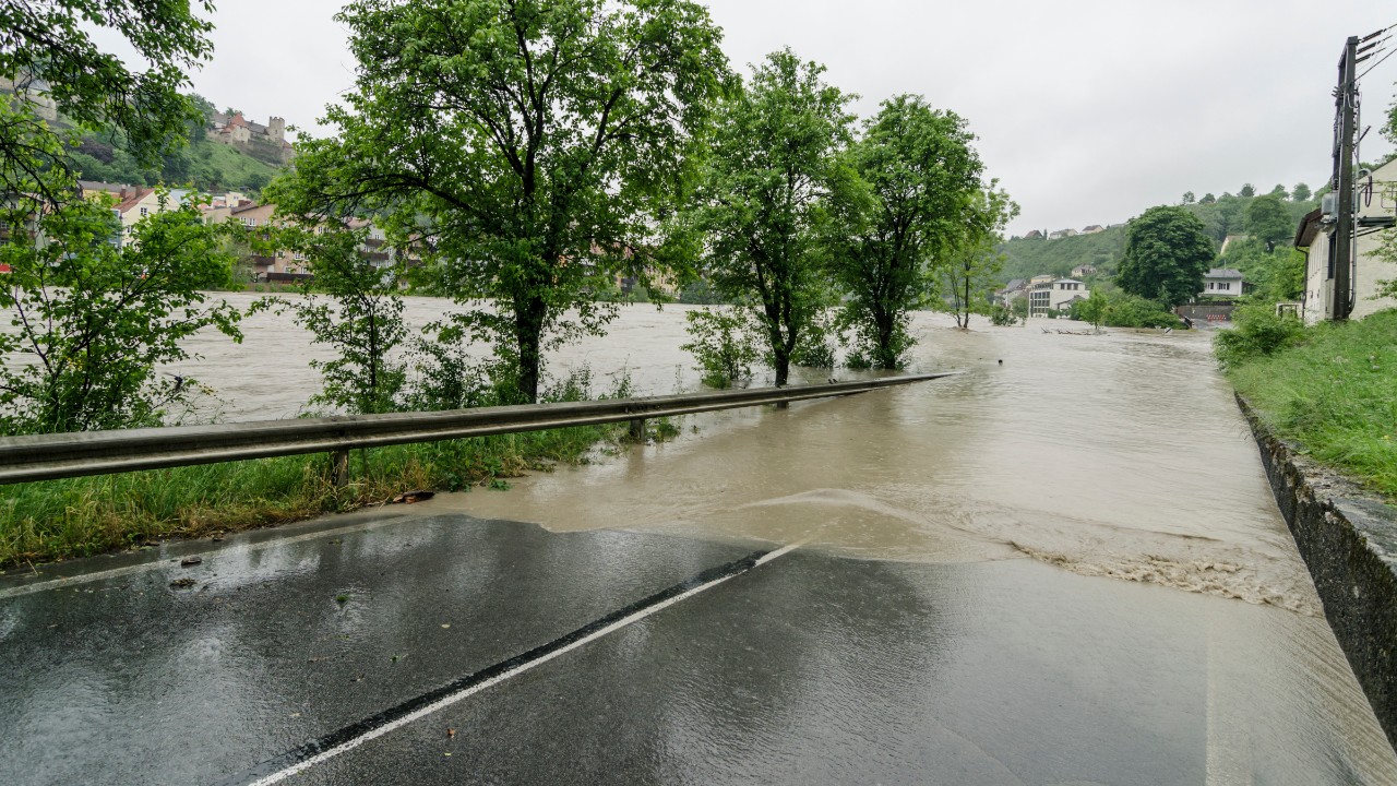 Eine Überflutete Straße neben einem übertretenden Fluss.