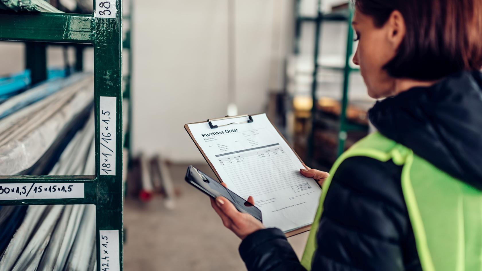 Arbeiterin prüft im Materiallager einen Auftrag