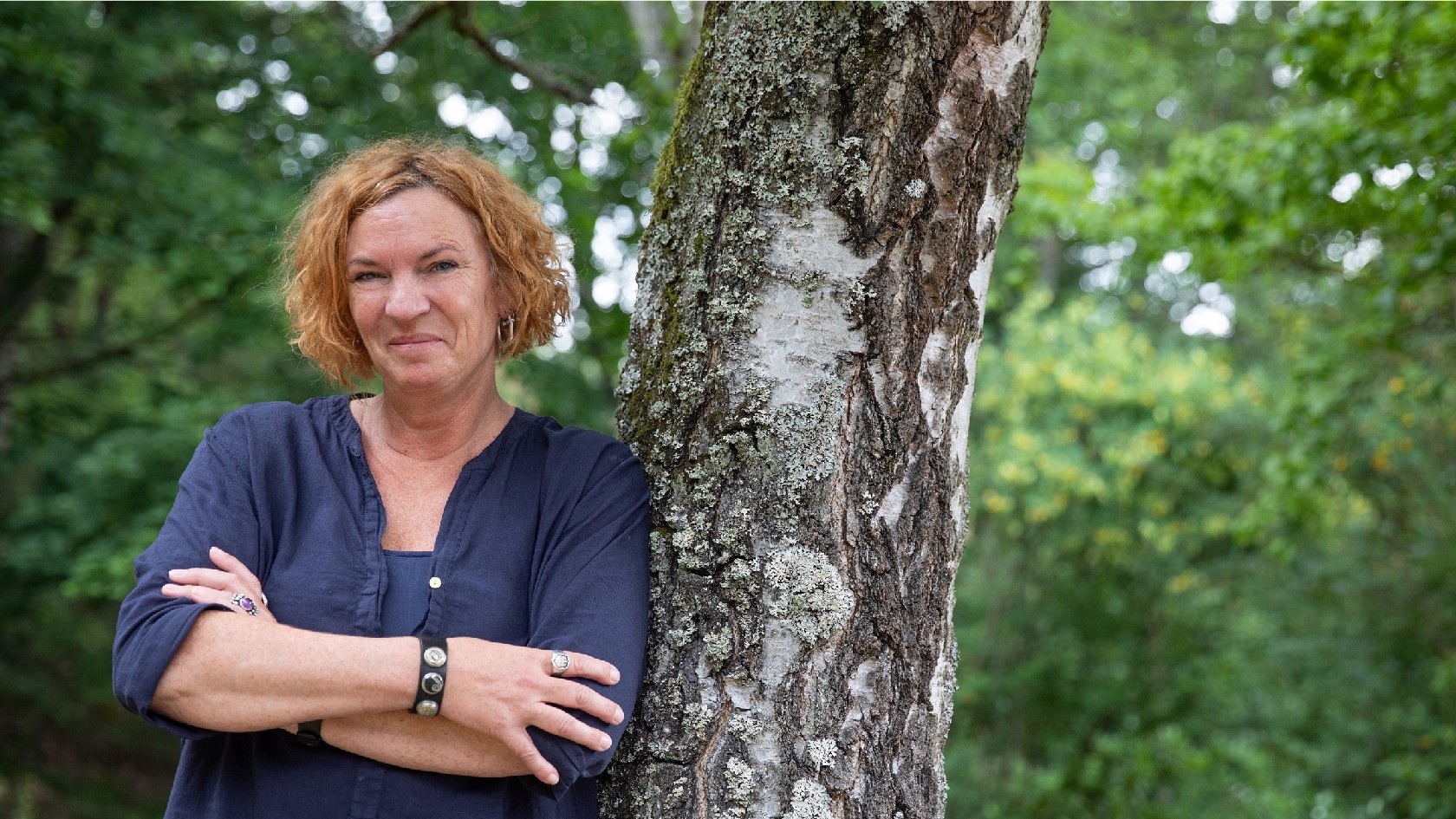 Resolute Frau lehnt am Baum