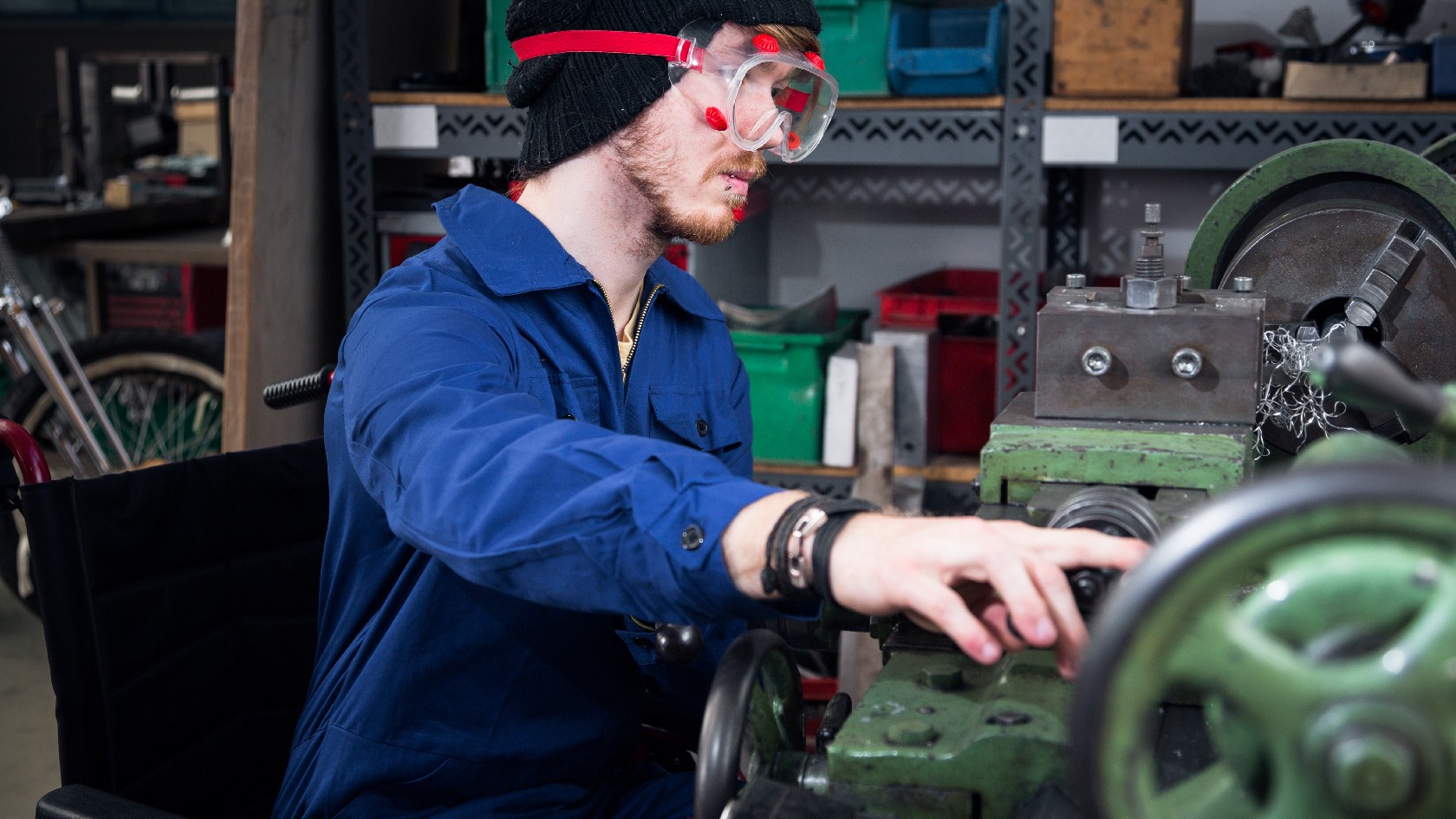 Junger Mechaniker an der Drehmaschine im Rollstuhl