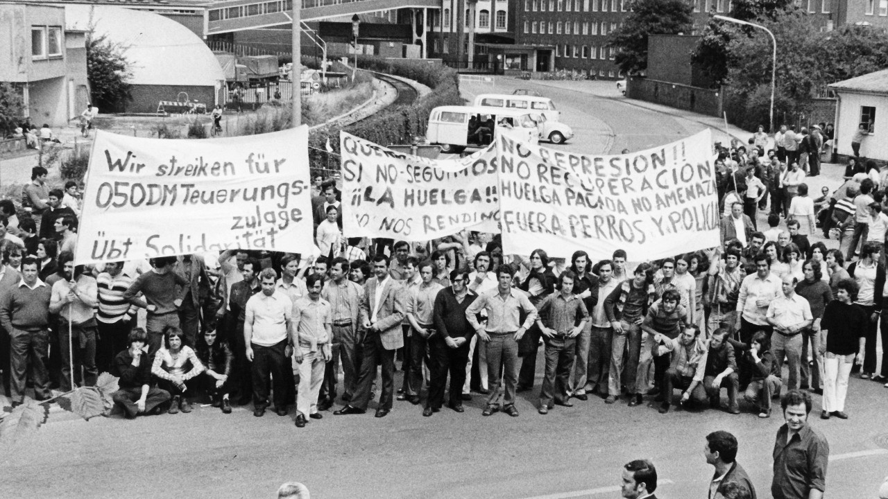 Rund 2.400 meist spanische Gastarbeiter machen am Donnerstag, den 19.07.1973, vor den Toren der Hella-Werke in Lippstadt mit Transparenten auf ihre Forderung nach einem Teuerungszulage von fünfzig Pfennig pro Stunde aufmerksam. Spontane Streiks wie dieser wurden despektierlich auch „wilde Streiks“ genannt