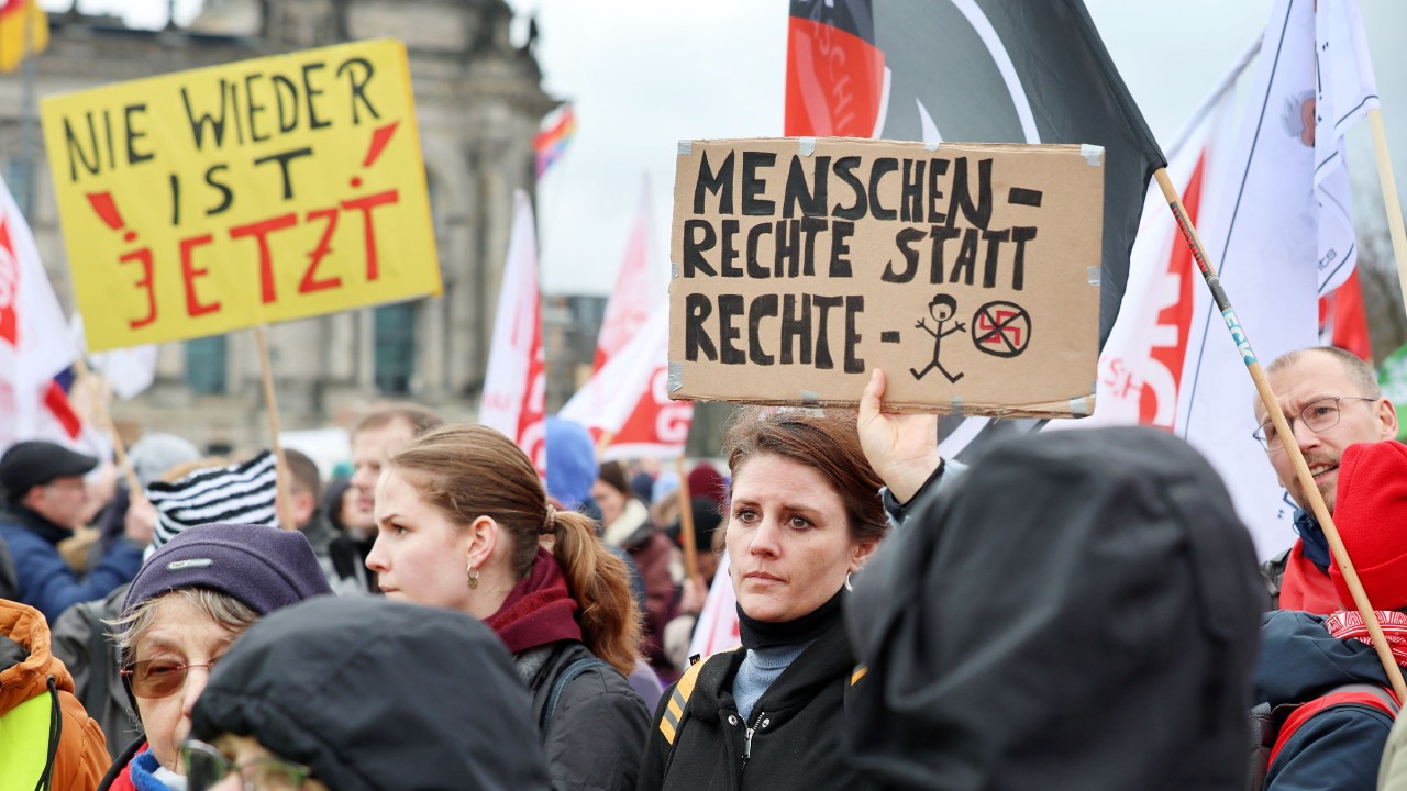 Menschenmenge bei einer Demo. Eine Frau hält ein Schild hoch mit der Aufschrift „Menschenrechte statt rechte Menschen“.