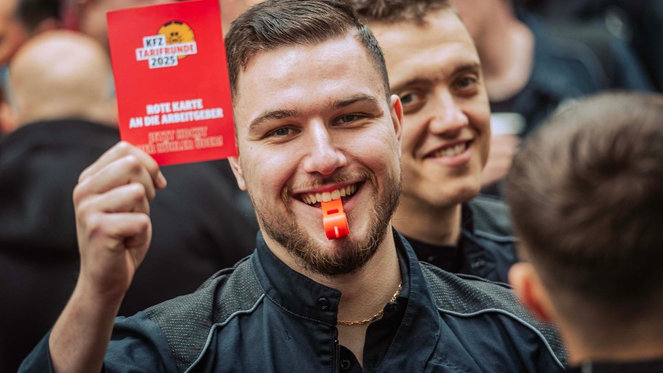 Besch&auml;ftigter zeigt Arbeitgebern w&auml;hrend der Kfz-Tarifrunde 2025 die symbolische Rote Karte.