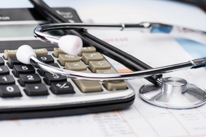 Ein Stethoskop liegt auf einem Taschenrechner und Unterlagen