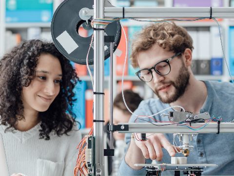 Zwei junge Ingenieure arbeiten an einem 3D-Drucker.