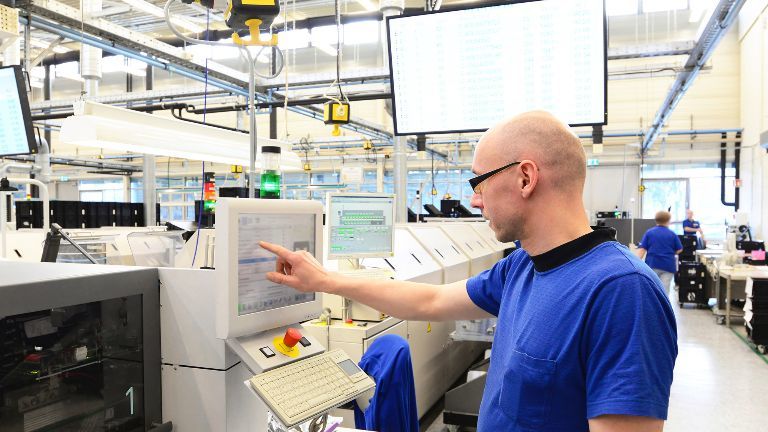 Ein Beschäftigter bedient den Monitor einer Maschine in einer High-Tech-Fabrik.