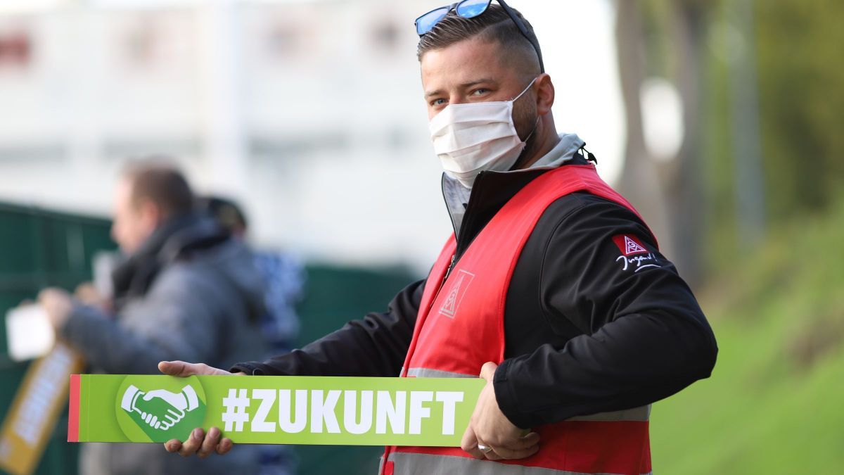 Beschäftiger mit Mund-Nasen-Schutz hält ein Schild auf dem das Wort Zukunft steht