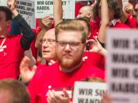 Delehgierte auf dem Gewerkschaftstag halten bei der Aktion der IG Metall Jugend Schilder hoch.